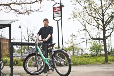 man unlocking a beryl bike at a beryl bay near train station in Norwich