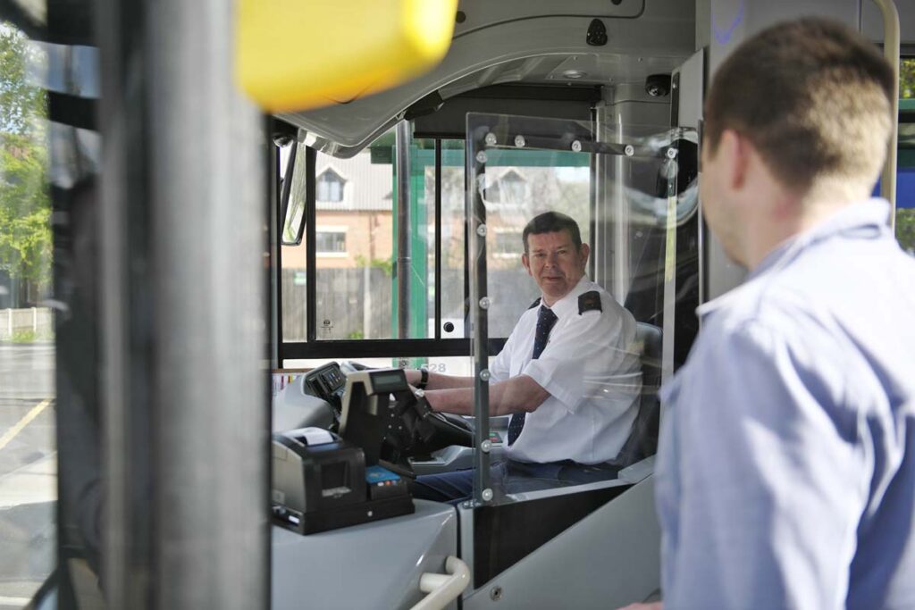 This is an image of a man catching the bus and talking to the bus driver.