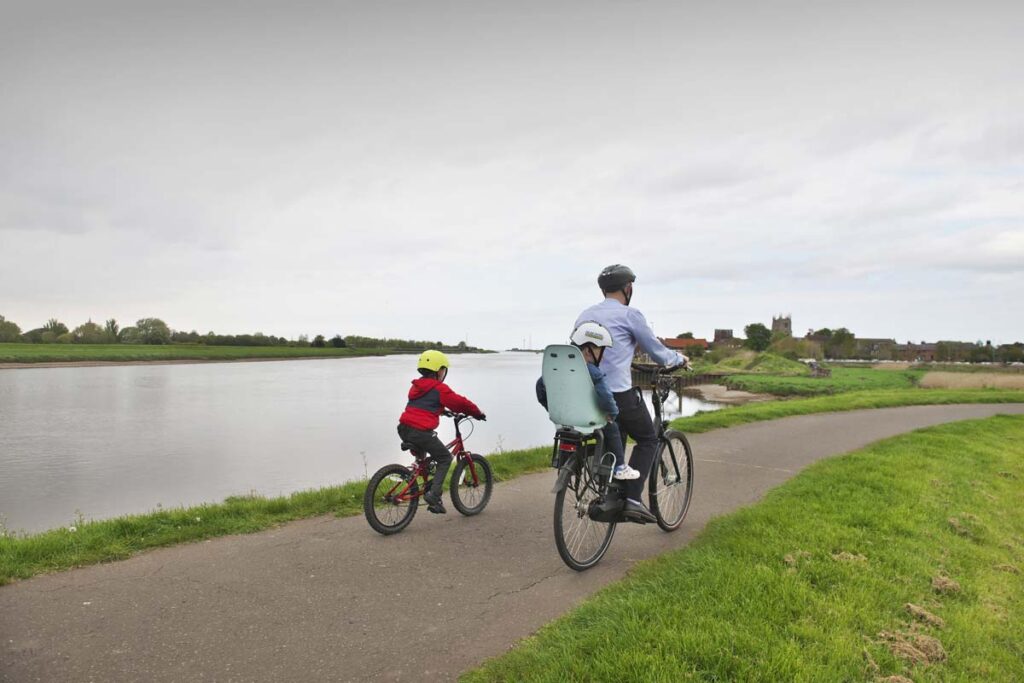 This is an image of a young family cycling along the river in King's Lynn in Norfolk