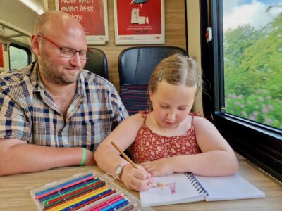 father and daughter colouring on the train