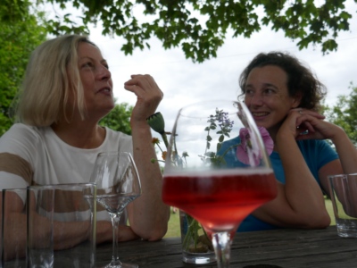 two women at a vineyards chatting at the table with a couple glass of wine